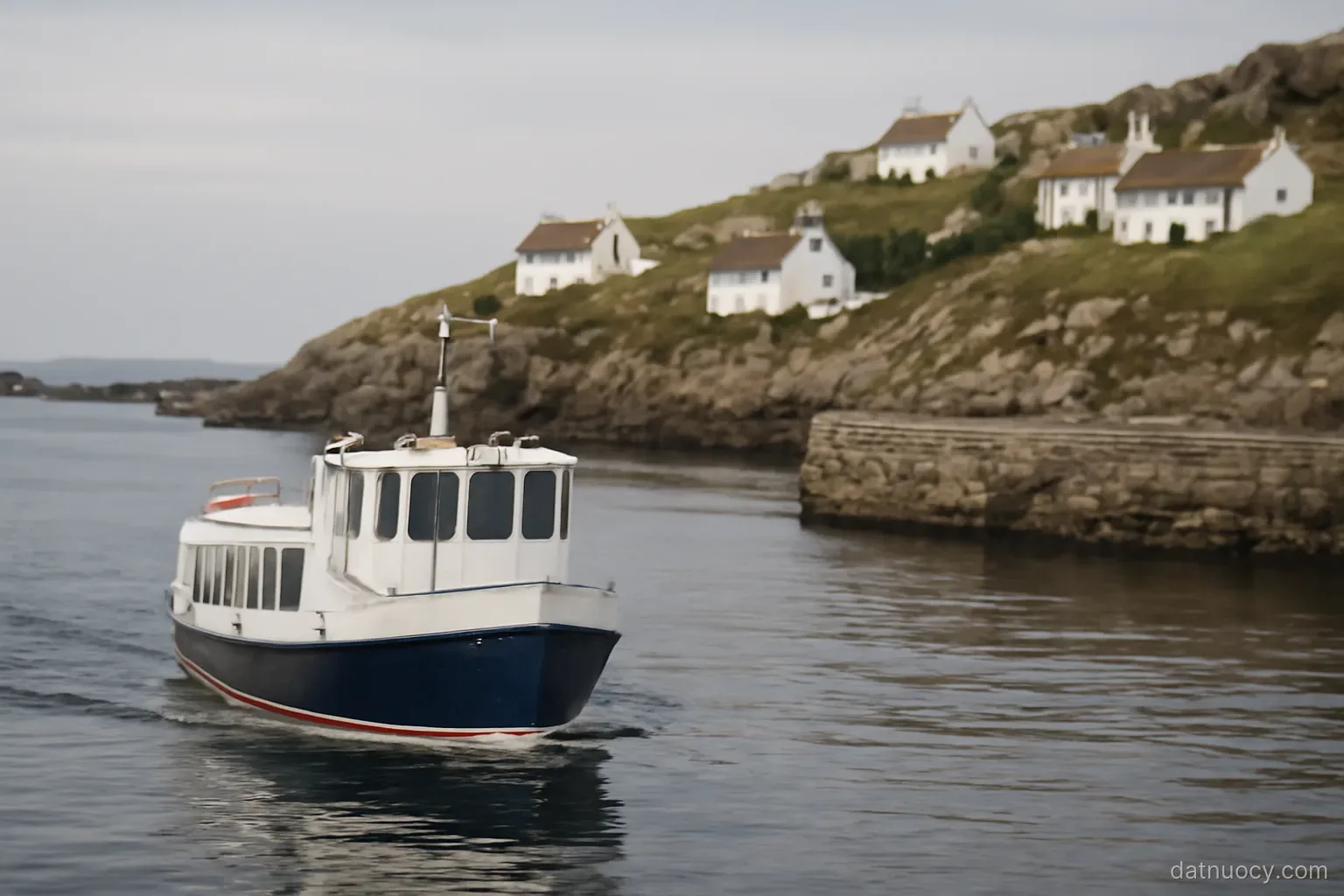 A small ferry approaching a rocky island harbour with white houses on the slope above, calm sea